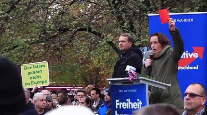 AfD-Vize Beatrix von Storch zeigt auf der Demo am 7. November Angela Merkel die rote Karte.