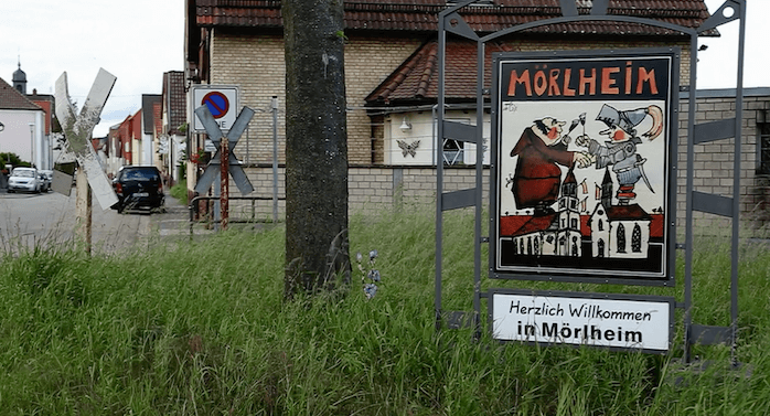 Das erste Haus gleich rechts hinter dem 1983 stillgelegten Bahnhalt der Strecke Landau-Herxheim ist das Haus, in dem am 19. Mai 2016 Gertrud Lange (86) von Einbrechern ermordet wurde (Screenshot SWR Zur Sache! Rheinland-Pfalz "Ein Dorf in Angst. Seniorin von Einbrechern getötet")