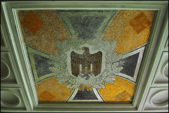 Eagle grasping swastika at Krampnitz. Source.