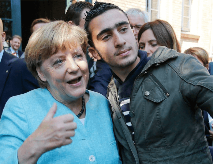 Die Security sagte nein, Bundeskanzlerin Angela Merkel (CDU) erlaubte dennoch beim Besuch einer Erstaufnahmeeinrichtung für Flüchtlinge der Arbeiterwohlfahrt in Berlin-Spandau am 10. September 2015 Selfies von sich mit jungen Syrern wie hier mit Anas Modamani (19). „Merkel sehr gut“, sagte auch der 23-jährige Flüchtling Hammd der Berliner Zeitung. Die ehrenamtliche Helferin Julia Grewe dagegen klagte gegenüber der Kanzlerin: „Wir können das nicht mehr sehr lange machen, irgendwann müssen wir auch wieder in unseren Berufen arbeiten“. Und: Weil es an Unterkünften mangelt bekommt ein Teil der Flüchtlinge Gutscheine für Übernachtungen. Doch immer mehr Betreiber von Hostels und Herbergen, schüttelten nur noch den Kopf, berichtete Julia Grewe, nicht weil sie etwas gegen Flüchtlinge hätten. Das Lageso, das Berliner Landesamt für Gesundheit und Soziales, sei ein äußerst säumiger Zahler. Manche Betreiber von Unterkünften hätten Außenstände von etlichen Tausend Euro (Foto: Facebook/Anas Modamani)