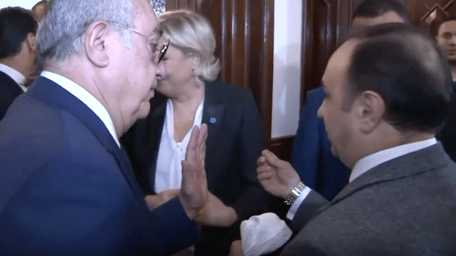 Ein Mitarbeiter von Großmufti Scheich Abdel-Latif Derian versucht, Marine Le Pen ein weißes Kopftuch zu übergeben. (Screenshot: YouTube)
